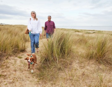 Couple walking their dog on the dunes at Seashore