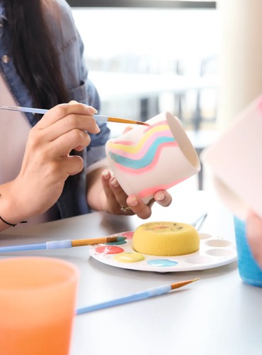 Holidaymakers paint pottery mugs in Pic 'n' Paint Pottery.
