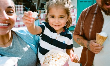 A tot enjoys popcorn and ice cream in the sunshine.