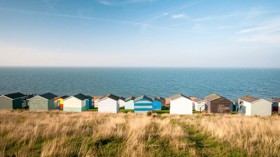 Colourful beach huts facing the calm Atlantic sea at Whitstable, Kent