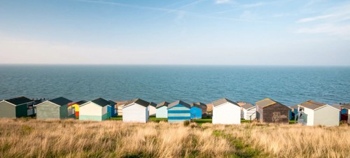 Colourful beach huts facing the calm Atlantic sea at Whitstable, Kent
