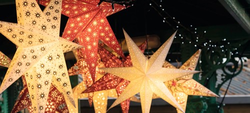Festive lighting hangs from a Christmas market stall.