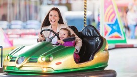 Mother and daughter in bumper car at fun fair