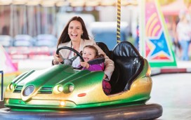 Mother and daughter in bumper car at fun fair