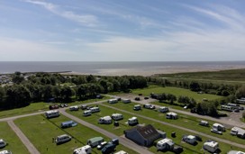 A drone image shows the Lakeland Leisure Park touring area with coastal views beyond it.