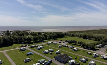 A drone image shows the Lakeland Leisure Park touring area with coastal views beyond it.