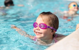 A young girl wearing goggles swims in the outdoor pool at Devon Cliffs.
