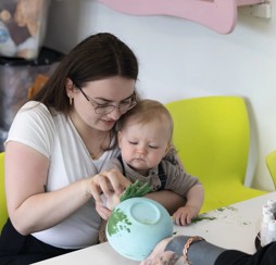 A tot adds his handprint design to a piece of pottery.