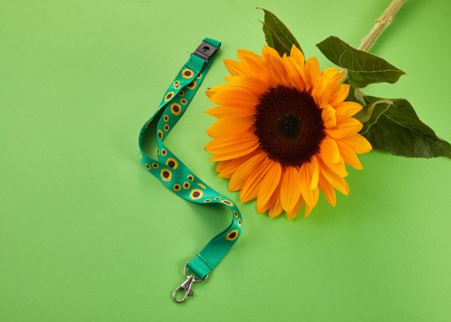 An image of a Sunflower lanyard next to a sunflower