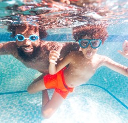 A father and son wearing googles pose under the water in Kent Coast's swimming pool.