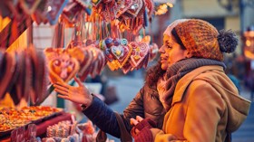 Friends peruse the sweet treats on a Christmas market stall.