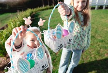 two sisters doing an easter egg hunt in the grass