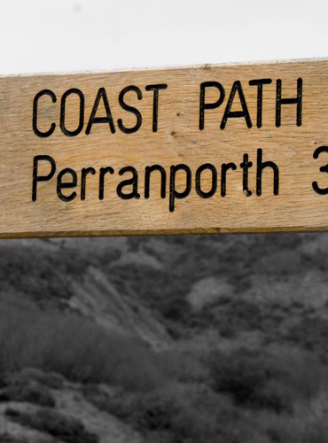 A sign points towards Perranporth on the South West Coast Path in Cornwall.