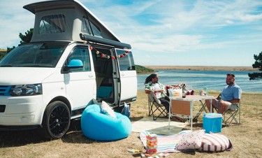 A couple of adults relaxing by a motorhome in Littlesea