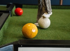 A competitor uses their feet to guide the coloured footballs into the pockets in a game of foot pool.
