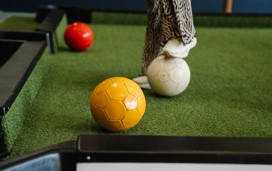 A competitor uses their feet to guide the coloured footballs into the pockets in a game of foot pool.