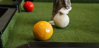 A competitor uses their feet to guide the coloured footballs into the pockets in a game of foot pool.