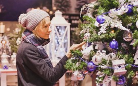 A woman admires a Christmas tree at a Christmas market.