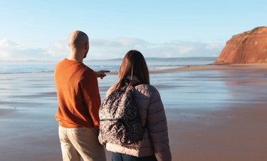 A couple stroll hand-in-hand along the beach at Devon Cliffs.