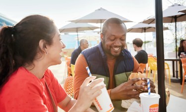 Couple enjoying Burger King food at the outdoor piazza in Skegness Holiday Park