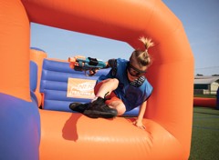 A guest jumping over the inflatables playing Nerf Training Camp