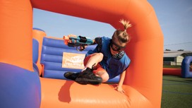 A guest jumping over the inflatables playing Nerf Training Camp
