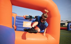 A guest jumping over the inflatables playing Nerf Training Camp
