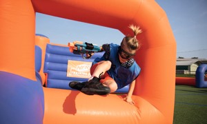 A guest jumping over the inflatables playing Nerf Training Camp