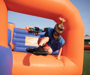 A guest jumping over the inflatables playing Nerf Training Camp