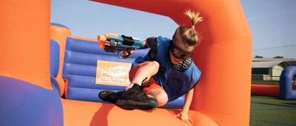 A guest jumping over the inflatables playing Nerf Training Camp