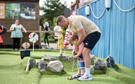 A dad helps his toddler son at the Crazy Golf Course in Lakeland.