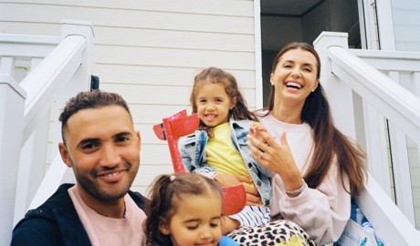Family sitting on the steps outside their caravan.